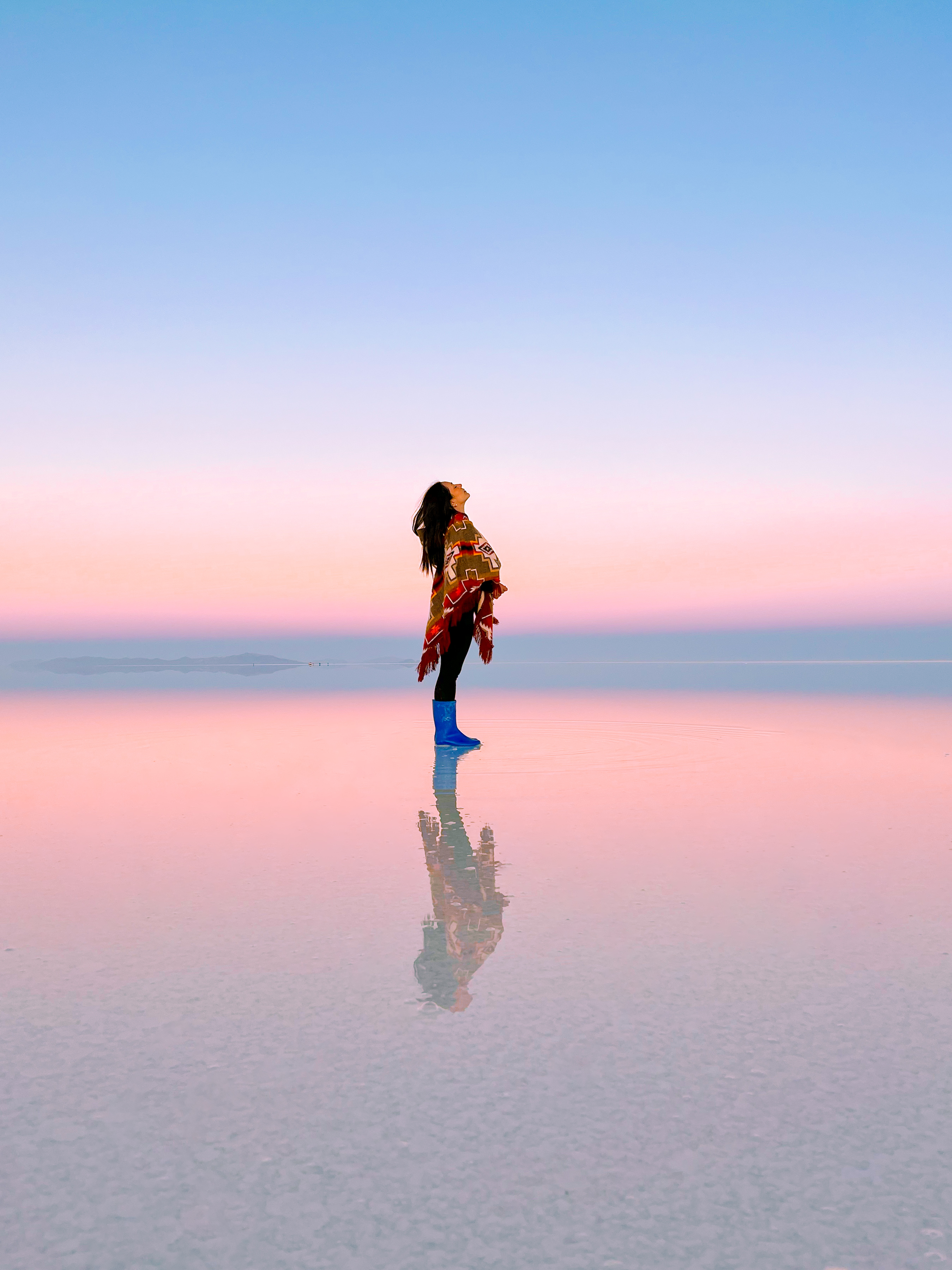 Salar de Uyuni bajo un cielo rosado, con el cielo reflejado en el agua.
